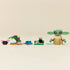 LEGO Star Wars Grogu’s Homestead set displayed in a row on a neutral surface, showing Grogu figure, small landscape builds, blue creature, food elements, and accessories arranged for scale.