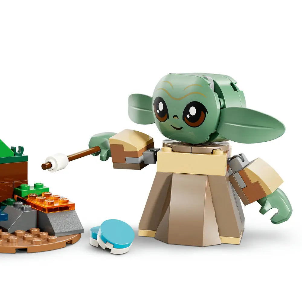 LEGO Star Wars Grogu figure shown up close in light green and tan plastic with large expressive eyes, wide ears, and blocky robe details, holding a small accessory and posed on a neutral studio background.