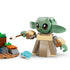 LEGO Star Wars Grogu figure shown up close in light green and tan plastic with large expressive eyes, wide ears, and blocky robe details, holding a small accessory and posed on a neutral studio background.