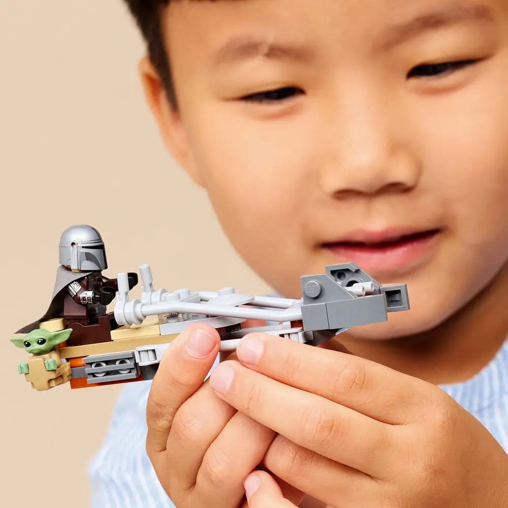 LEGO Star Wars speeder bike play scene with gray and tan plastic pieces, shown in a child’s hands while assembling parts, emphasizing hands-on construction, focus, and imaginative indoor play.
