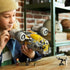 LEGO Star Wars Razor Crest vehicle, gray and yellow plastic starship with broad fuselage, twin engines and action-play theme, held by a builder in a workshop setting with minifigures.