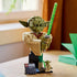 LEGO Star Wars Yoda display features olive green and tan plastic surfaces, a sculpted Jedi bust holding a green lightsaber, display plaque and minifigure presented on a tabletop near a window.