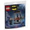 LEGO Batman building set package front showing black and dark blue cardboard artwork, glossy printed finish, Batman logo, Bruce Wayne minifigure, transforming Batsuit chamber, red laser bars, age 7+ label, and 35-piece count.
