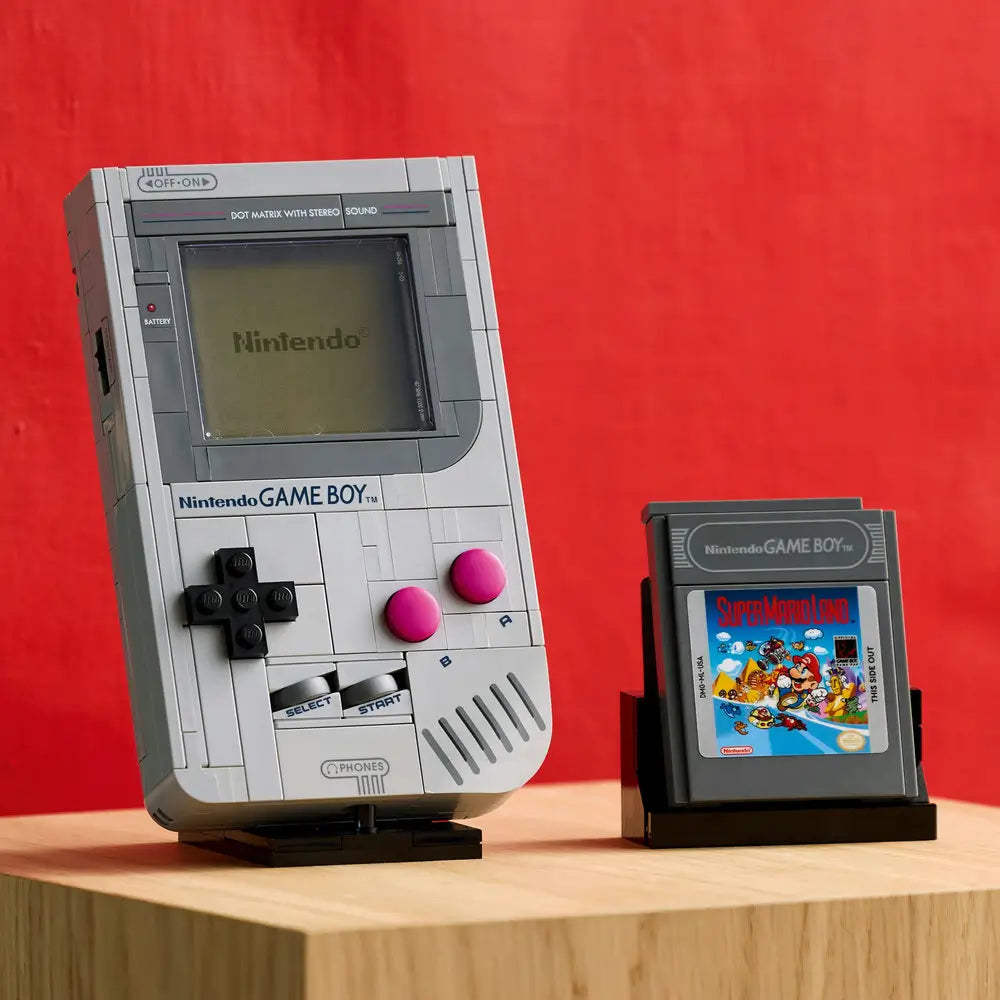 LEGO-built Nintendo Game Boy with detailed D-pad and pink buttons displayed beside two brick-built game cartridges featuring The Legend of Zelda and Super Mario Land designs.