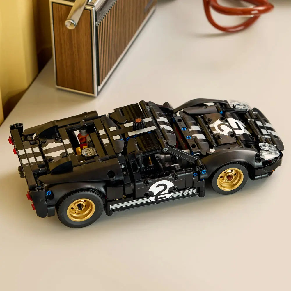 LEGO Technic Ford GT40 Mk II model displayed fully built with black bodywork, white racing stripes, gold wheels, low-profile stance, and realistic proportions resting on a light-colored table.