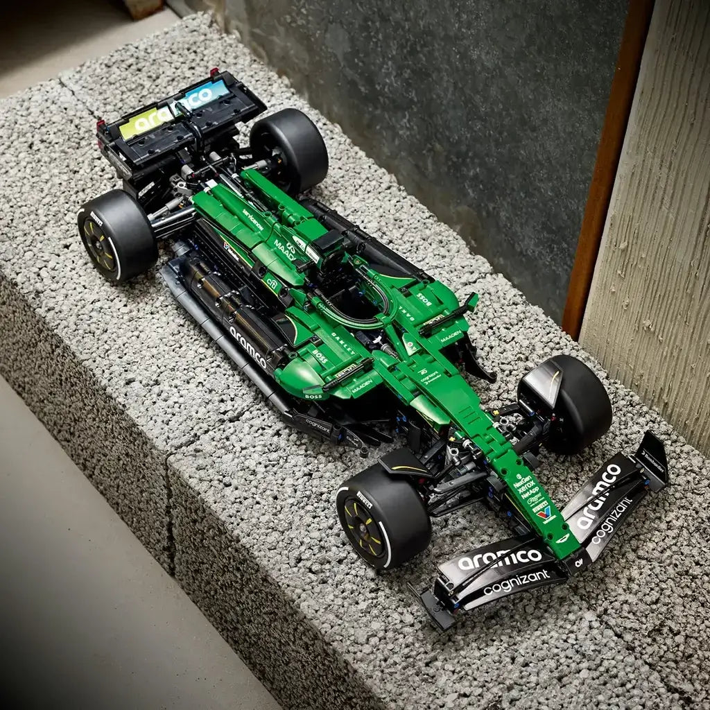 LEGO Technic Aston Martin Aramco AMR25 F1 car in green and black bricks features racing tires, aerodynamic bodywork and sponsor graphics, displayed on a textured bench.