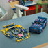 LEGO Technic Ford Mustang GT in dark blue plastic with pink and cyan stripes sits beside yellow, blue and pink interchangeable custom body panels arranged on a worktable.
