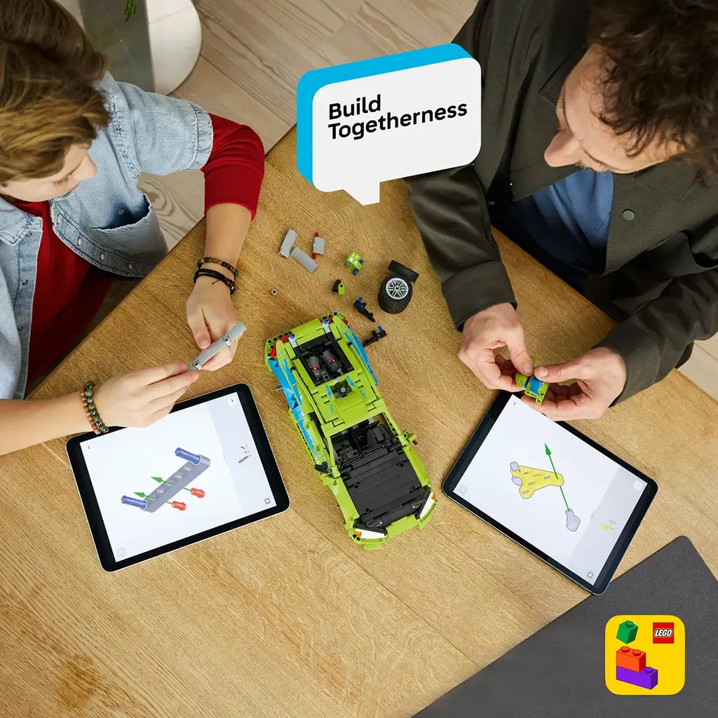LEGO Technic Mitsubishi Eclipse build in lime green and blue plastic bricks, assembled by two builders at a wooden table using tablets with digital LEGO instructions.