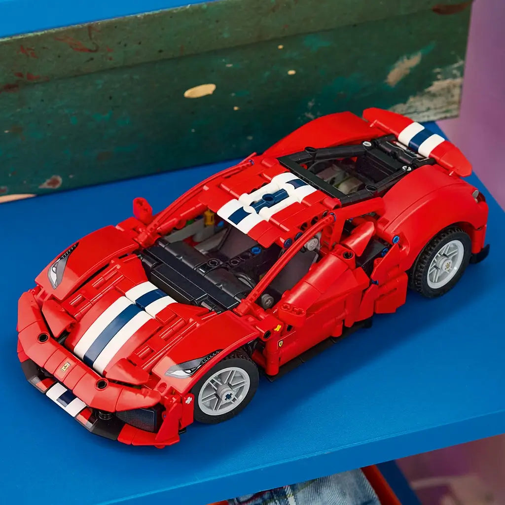 LEGO Technic Ferrari 488 Pista model in red plastic with white and blue racing stripes, silver wheels and a low aerodynamic body, displayed on a bright blue shelf.