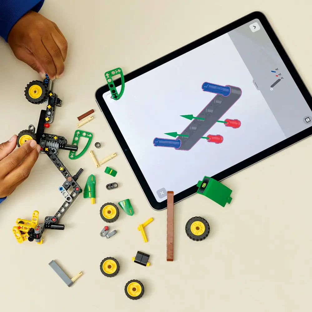 LEGO Technic John Deere 1470H Wheeled Harvester building activity shows a child attaching Technic beams, wheels, and crane joints while following step-by-step digital instructions on a tablet during hands-on construction.