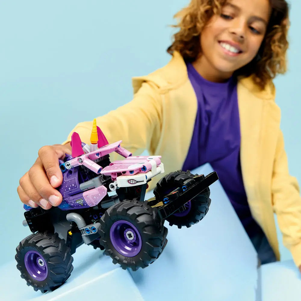 LEGO Technic Monster Jam Sparkle Smash lifestyle image shows a smiling child holding and rolling the unicorn-themed monster truck, emphasizing oversized tires, playful colors, and interactive pull-back play.
