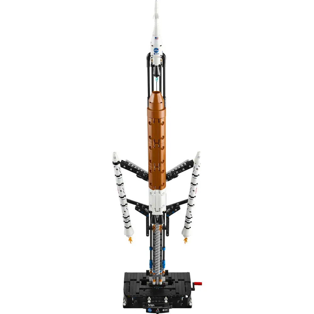 LEGO Technic NASA Artemis Space Launch System rocket model features white and orange plastic Technic panels, tall cylindrical stacked form, detailed engines, launch tower arms, and display base against a clean white background.