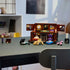 LEGO Wednesday Thing’s Apartment model displayed on a desk with included accessories like perfume bottles, a typewriter, a chest, and a small purple heart detail, illuminated by natural light.