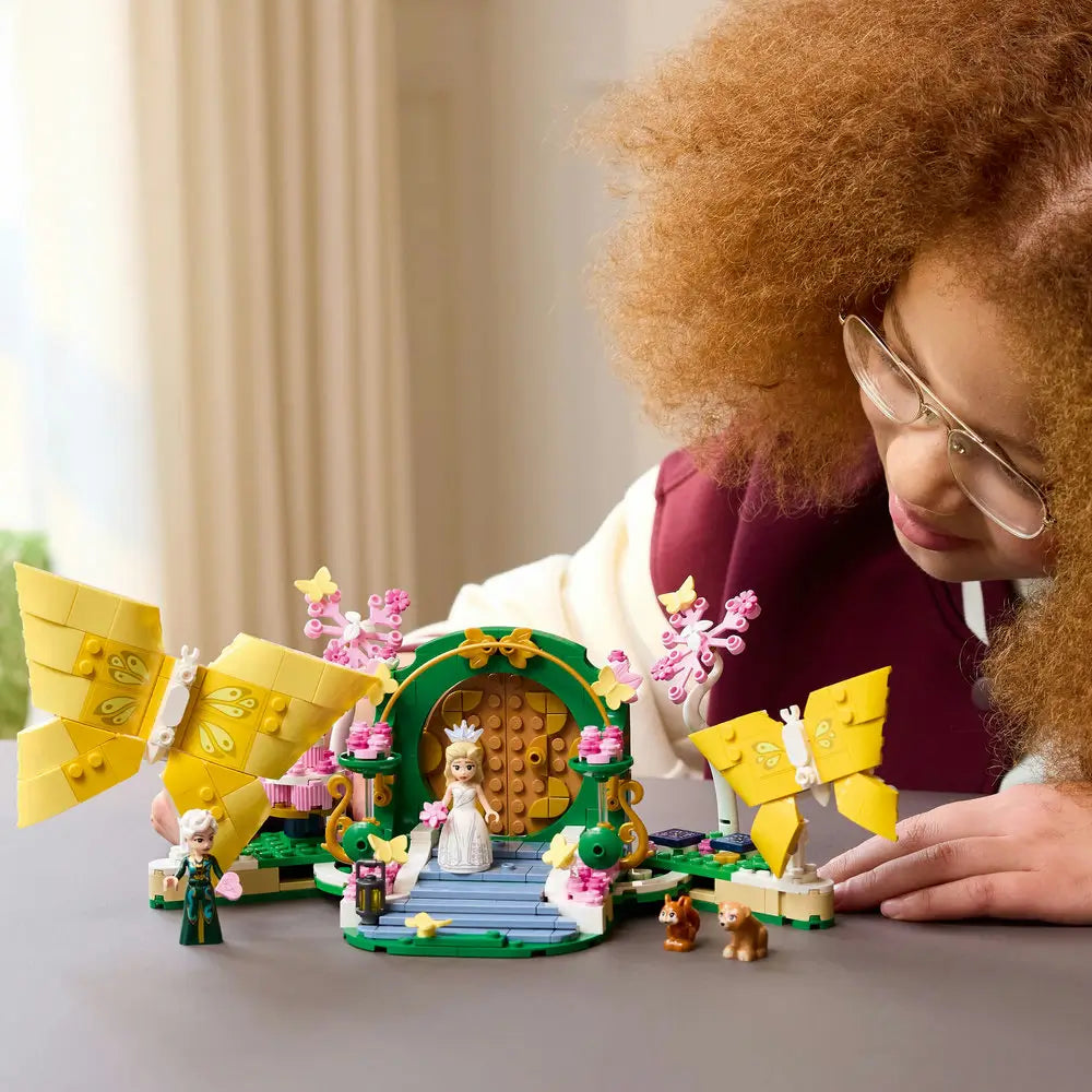 LEGO Wicked Glinda's Wedding Day playset features a child playing with the butterfly wedding display, Glinda and Elphaba mini-dolls in a bright indoor setting with detailed LEGO elements and realistic display presentation.