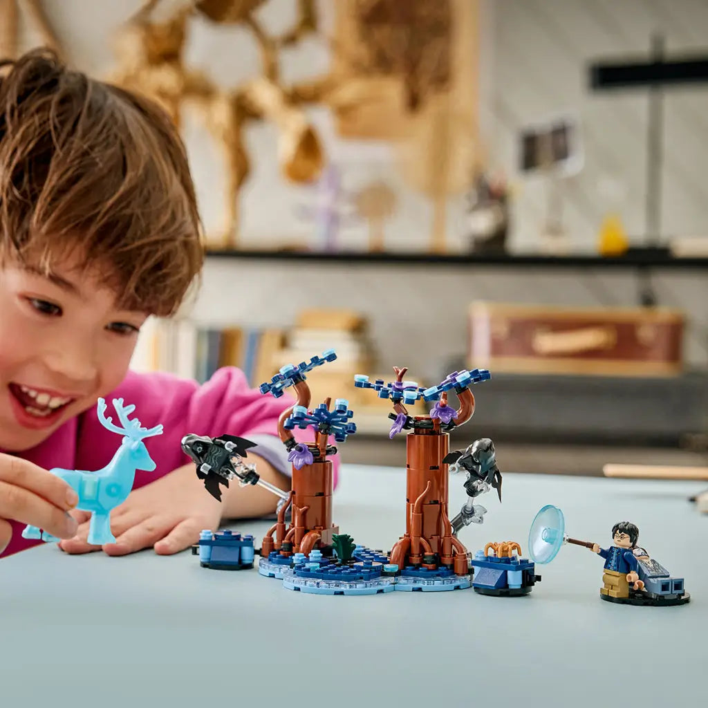 LEGO Harry Potter Forbidden Forest play scene shows a child in a pink top holding a translucent blue stag beside brown brick trees, Dementors, Harry Potter, and Sirius Black.