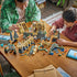 LEGO Harry Potter Hogwarts Castle East Wing building scene shows an adult and child assembling tan and gray castle sections, towers, bridge, minifigures, and basilisk.