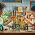 LEGO Harry Potter Hogwarts Castle East Wing play scene shows an adult and child moving minifigures around the tan castle, gray towers, bridge, and green basilisk.