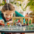LEGO Harry Potter Herbology Class playset features a child playing with the tan greenhouse, Professor Sprout and student minifigures on a reflective indoor tabletop with plants behind with detailed LEGO elements and realistic display presentation.