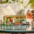 LEGO Harry Potter Herbology Class playset displays the tan greenhouse, magical plants, classroom accessories and minifigures arranged on a reflective indoor tabletop with greenery behind with detailed LEGO elements and realistic display presentation.