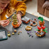LEGO Harry Potter Hogwarts Herbology Plants build scene shows a child assembling the green Mimbulus Mimbletonia in a brown pot beside red flowers, a Mandrake, and loose bricks.