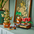 LEGO Harry Potter Hogwarts Herbology Plants display features green, red, brown, and purple brick plants in labeled pots arranged on a shelf beside framed botanical art.