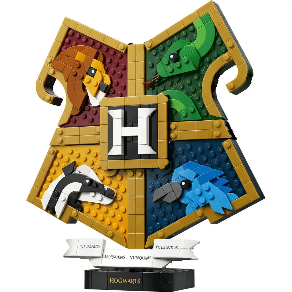 LEGO Harry Potter Hogwarts House Crest in gold-trimmed plastic bricks, featuring lion, snake, badger and eagle panels around a central H, displayed on a black Hogwarts stand.