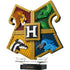 LEGO Harry Potter Hogwarts House Crest in gold-trimmed plastic bricks, featuring lion, snake, badger and eagle panels around a central H, displayed on a black Hogwarts stand.