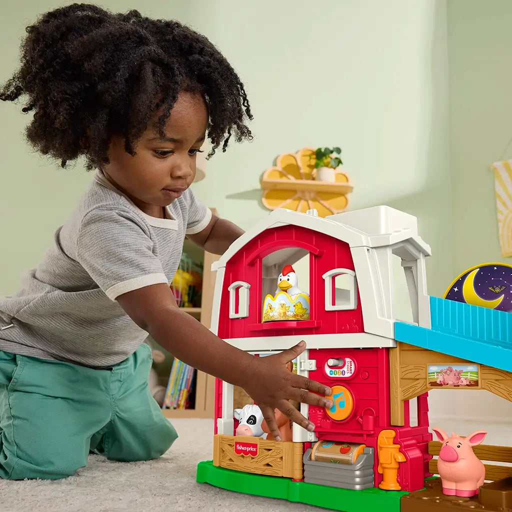 Child playing with Fisher-Price Little People Caring Fun Animal Farm playset, pressing buttons and engaging with animal figures.