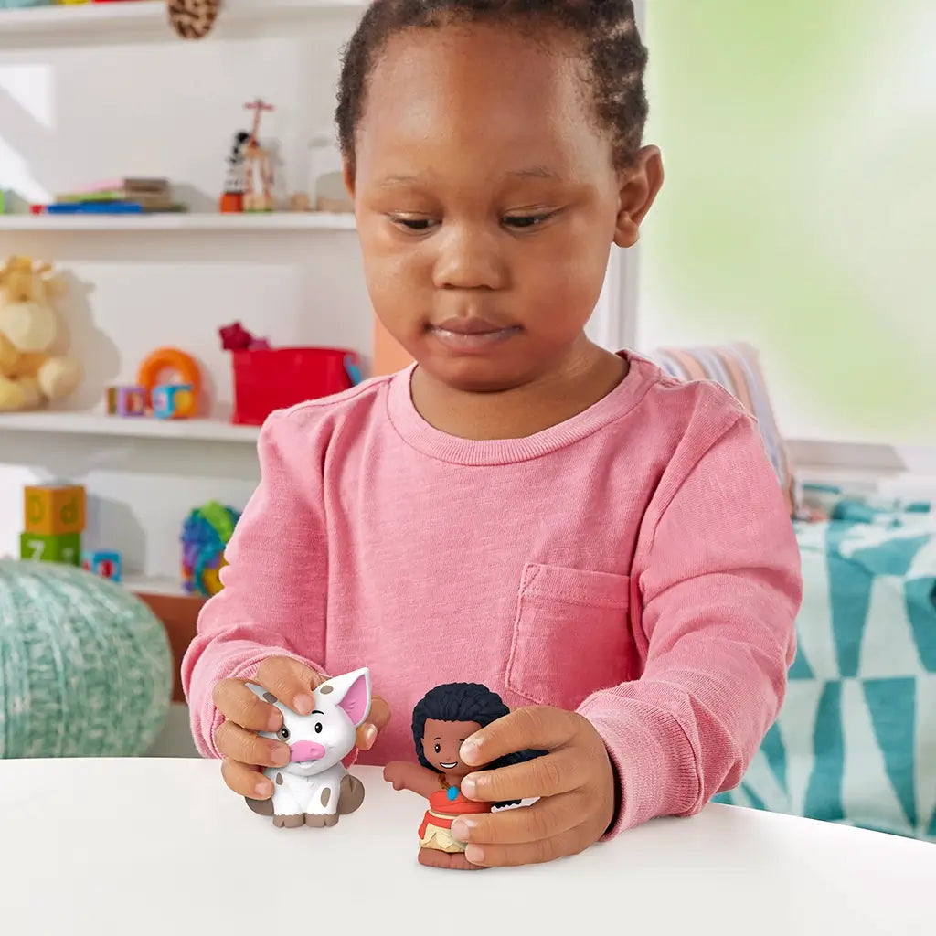 Disney Princess Moana toy play scene by Fisher-Price Little People with child holding brown Moana figure and white pig Pua, colorful nursery setting with shelves, toys, and soft indoor lighting