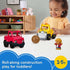 Smiling toddler playing with Fisher-Price Little People Work Around Town Vehicle Set, featuring red truck, yellow loader, brown ball, and two mini worker figures on a white table.