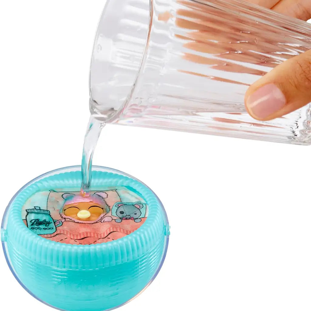 Hand pouring water into an L.O.L. Surprise! Baby Bundle Surprise container to activate a hidden reveal feature, showing the baby doll inside with pastel nursery graphics.