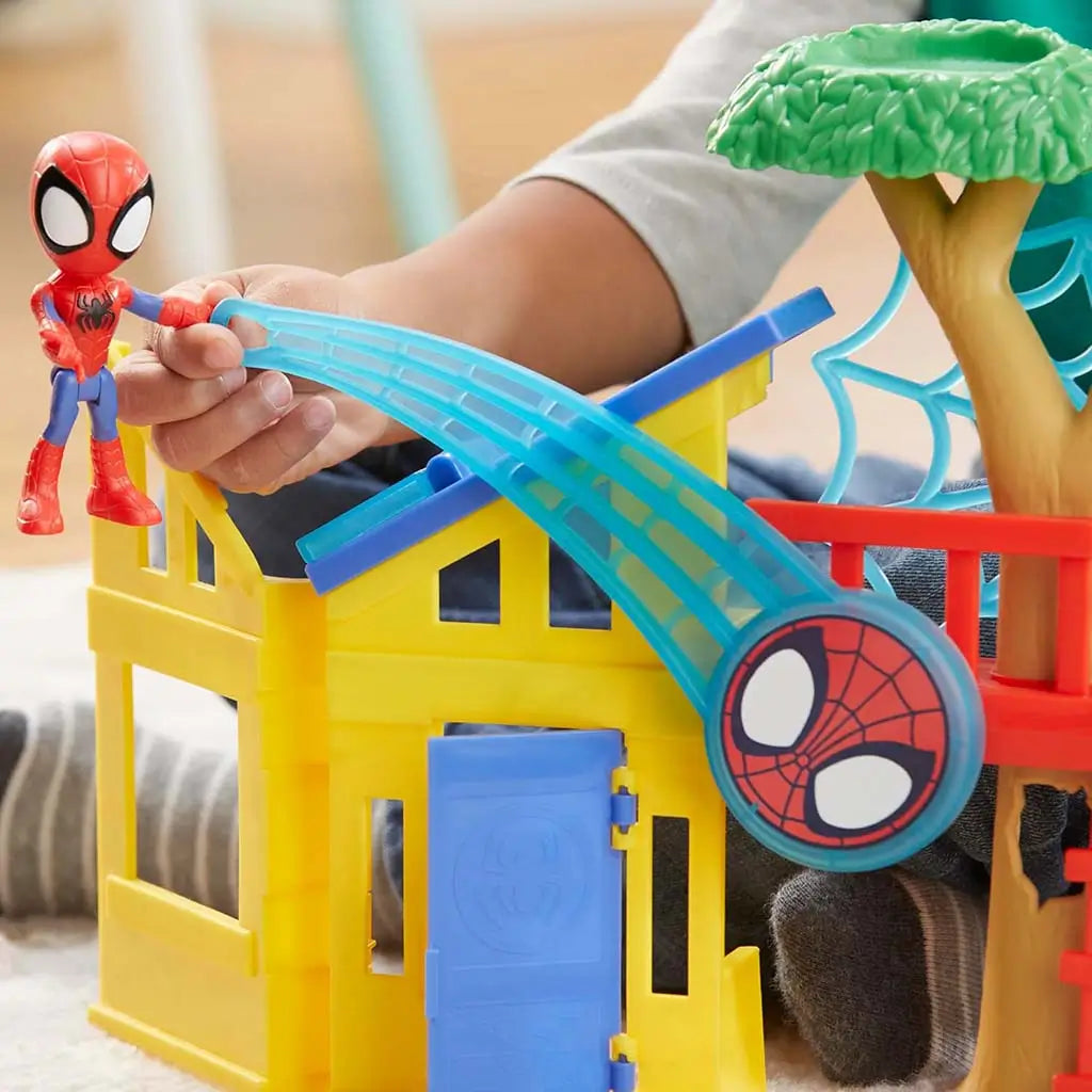 Marvel Spidey playground playset close-up shows child launching small Spidey figure along curved blue track attached to yellow house roof, highlighting hands-on interactive action feature.