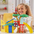 Marvel Spidey playground playset lifestyle scene shows child placing Spidey figure atop green tree canopy beside yellow house and blue track, demonstrating colorful oversized components for young kids.