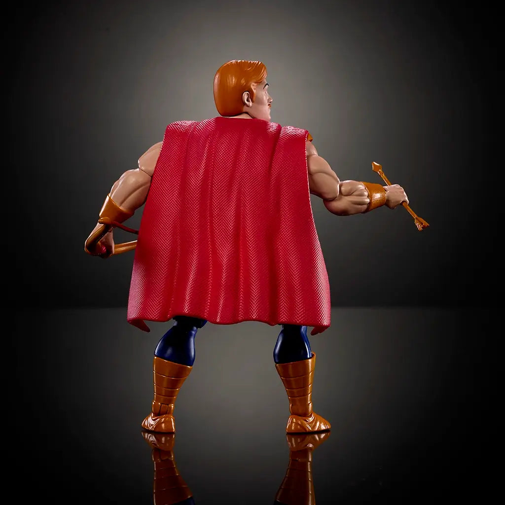 Rear view of Bow action figure highlighting red textured fabric cape, muscular back sculpt, blue pants, gold boots, and articulated arms, photographed from behind on a dark reflective studio surface.