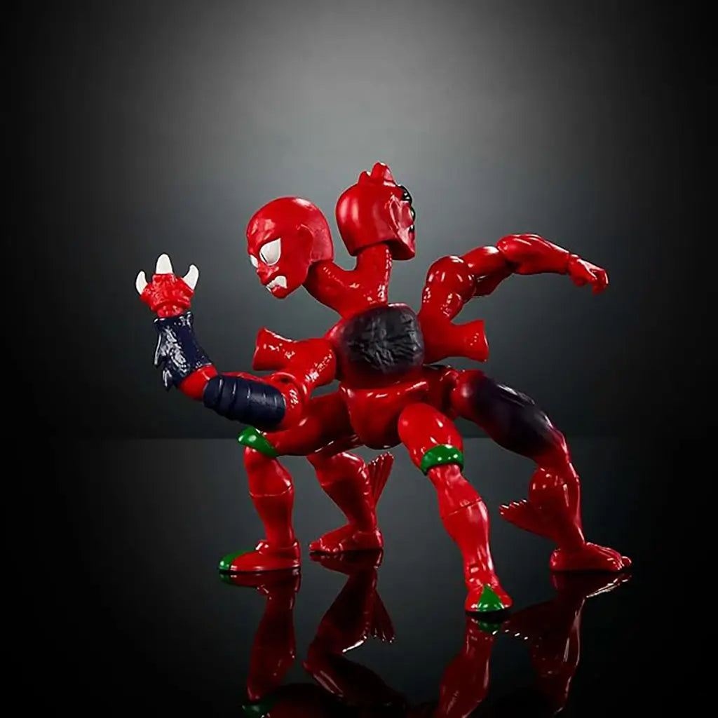 Masters of the Universe Modulok figure is posed in a dynamic side stance, showing shiny red segmented limbs, dual heads, dark forearm armor, and clawed hands against a dramatic gradient black studio backdrop.