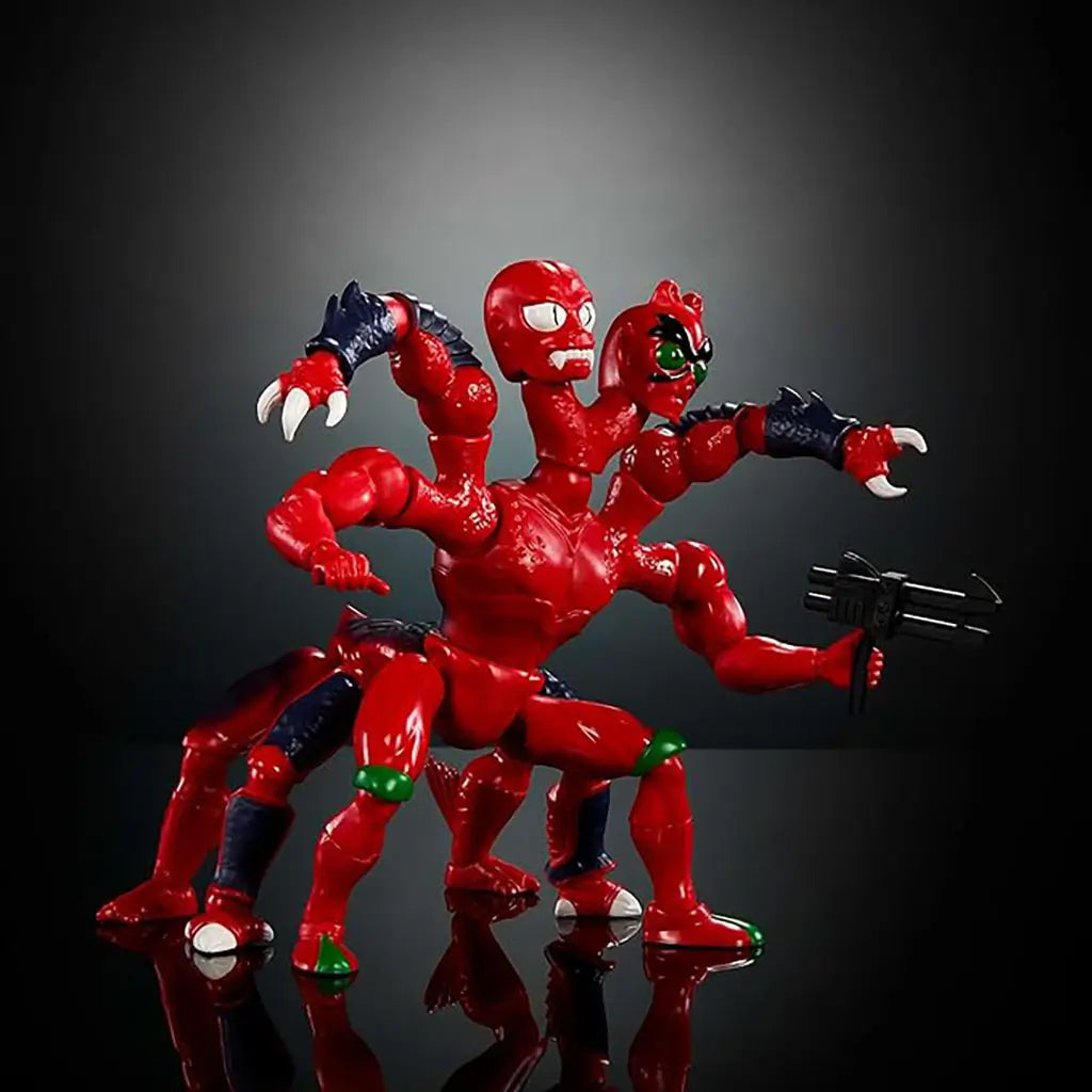 Masters of the Universe Modulok toy is posed with accessories, highlighting bright red articulated limbs, two distinct heads, dark armored forearms, and a retro creature design set against a dark studio background.