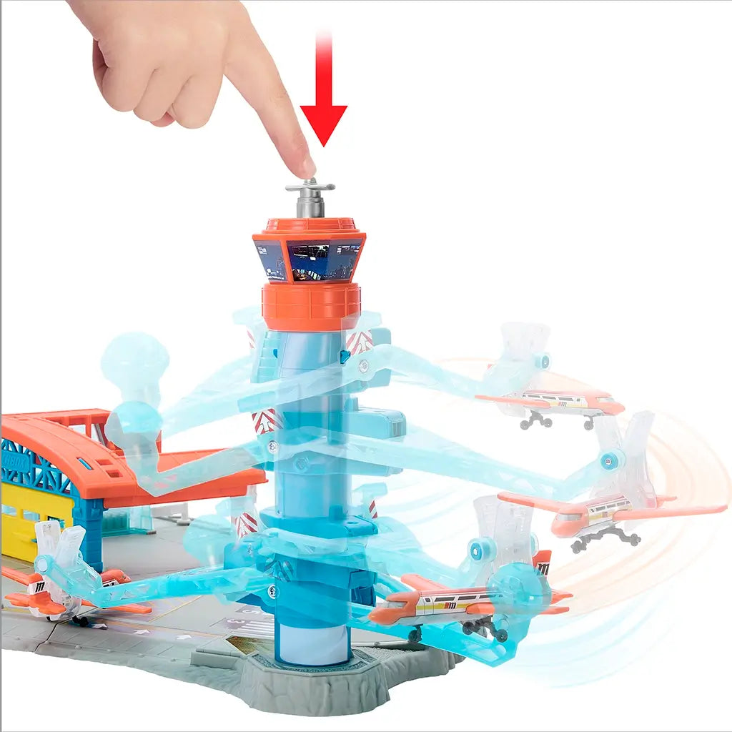 Matchbox Airport Takeoff Adventure toy playset with a red and blue plastic control tower, where a hand pushes the top button to launch orange planes on curved blue runways.