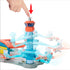 Matchbox Airport Takeoff Adventure toy playset with a red and blue plastic control tower, where a hand pushes the top button to launch orange planes on curved blue runways.