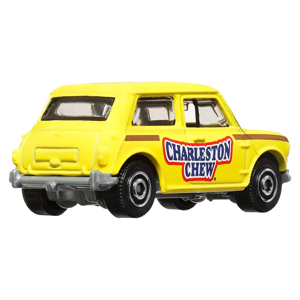 Matchbox Charleston Chew 1964 Austin Mini Cooper miniature in yellow with candy branding, brown stripe, chrome bumpers, and black wheels, viewed from rear angled perspective.
