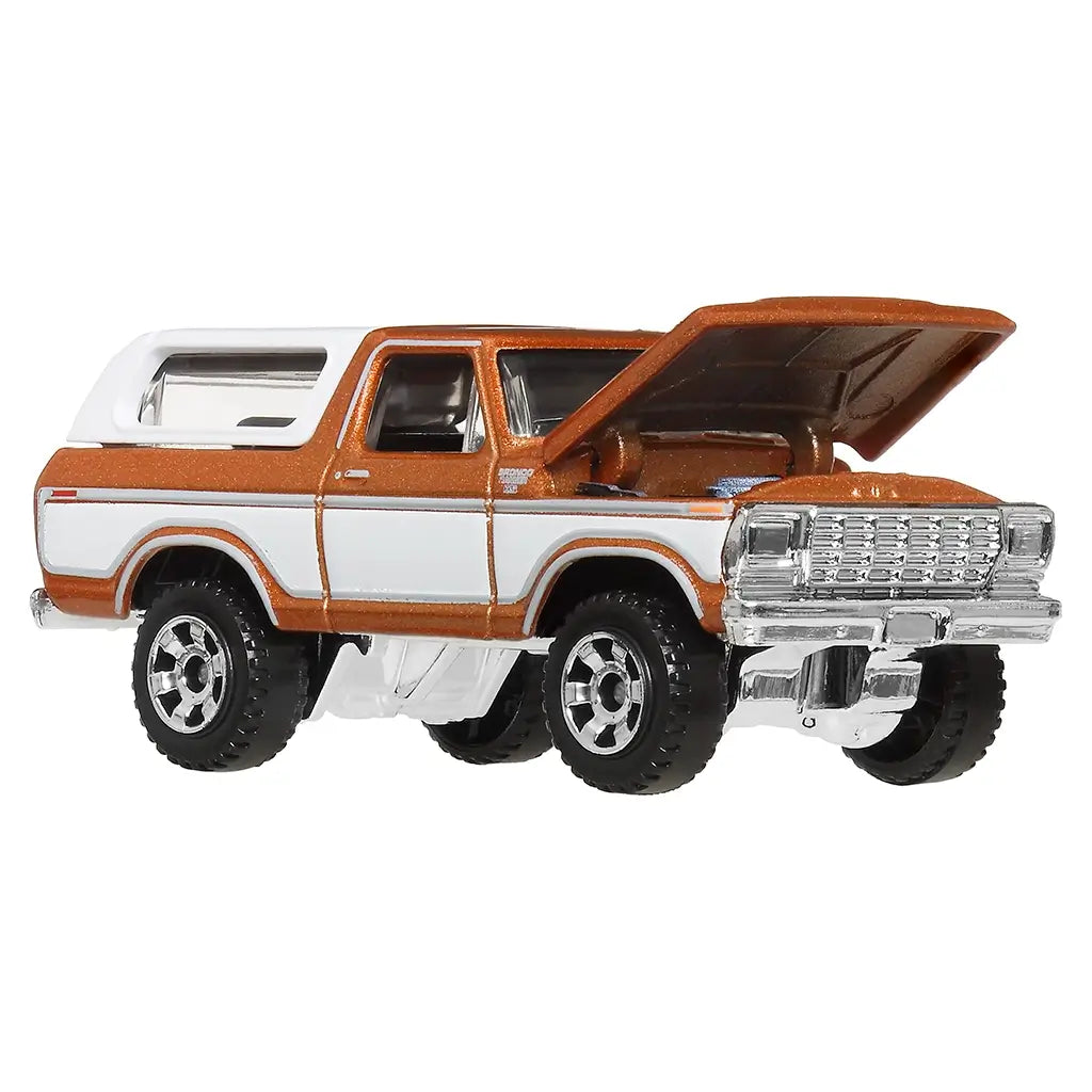Die-cast Matchbox 1978 Ford Bronco toy car with orange and white body shown at an angle with its hood open, revealing engine details and chrome grille for added realism.
