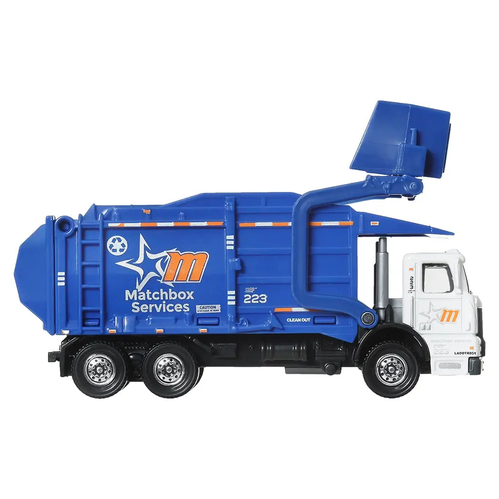 Matchbox Working Rigs Garbage King XL side view showing the blue metal garbage body, white cab, recycling logos, realistic proportions, and 1:64 scale design photographed on a white studio background.