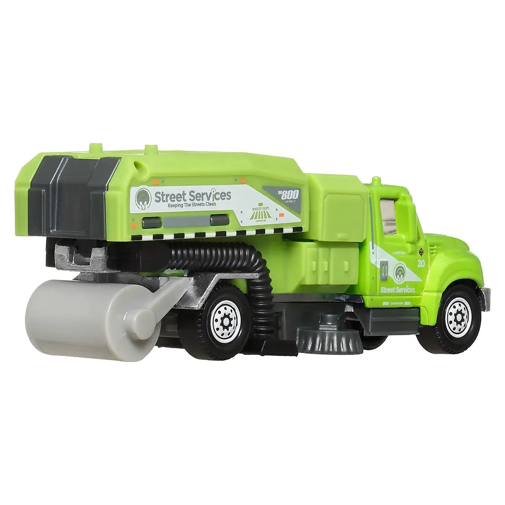 Rear angled view of Matchbox International WorkStar street sweeper toy truck in green with functional sweeping parts, black tubing, and bold service markings for urban maintenance play.