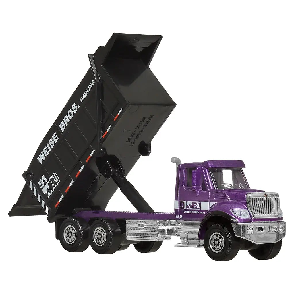 Matchbox International WorkStar 7500 Dump Truck toy in purple cab with silver accents and black dump bed, featuring Weise Bros. Hauling logo, displayed with raised dump bed.