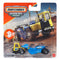 Matchbox Working Rigs MBX Road Scraper diecast construction vehicle in yellow and blue metal with molded industrial textures, articulated scraper body, rugged rolling wheels, and heavy-duty earthmoving design shown in retail packaging with a construction site background.