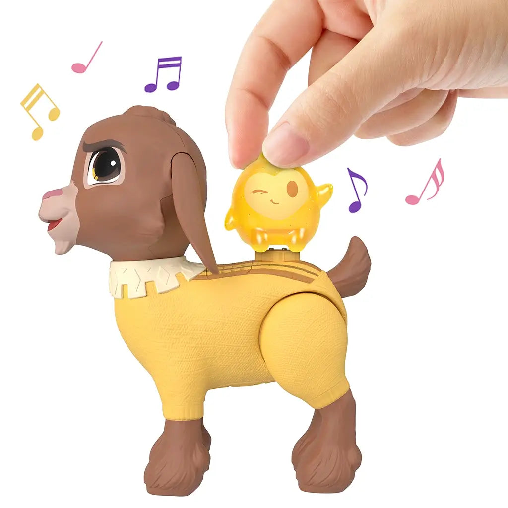 Hand places glittery yellow Star figure on back of Disney Wish Valentino goat toy, triggering musical sounds with colorful notes, promoting interactive play.