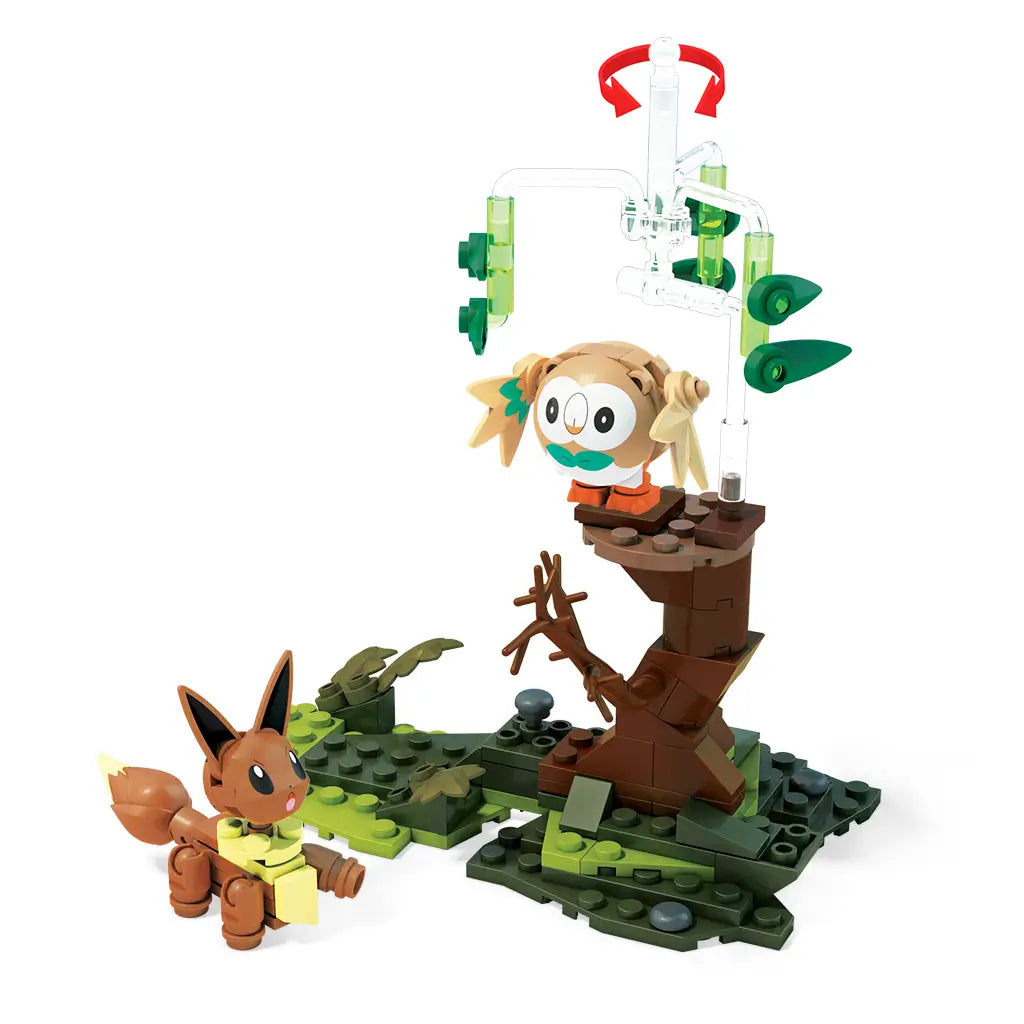 Mega Construx Pokémon Rowlet and Eevee set showing Rowlet perched on a brown brick tree with green spinning pieces, while Eevee stands on grassy terrain nearby.