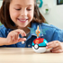 Smiling child in denim jacket playing with MEGA Pokémon Rotom building set, featuring orange Rotom figure with translucent blue wings emerging from a red and blue Poké Ball.