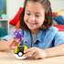 Child smiling while holding Mega Pokémon Sableye figure above yellow-and-black Ultra Ball building block case, showing imaginative play in a colorful bedroom setting.