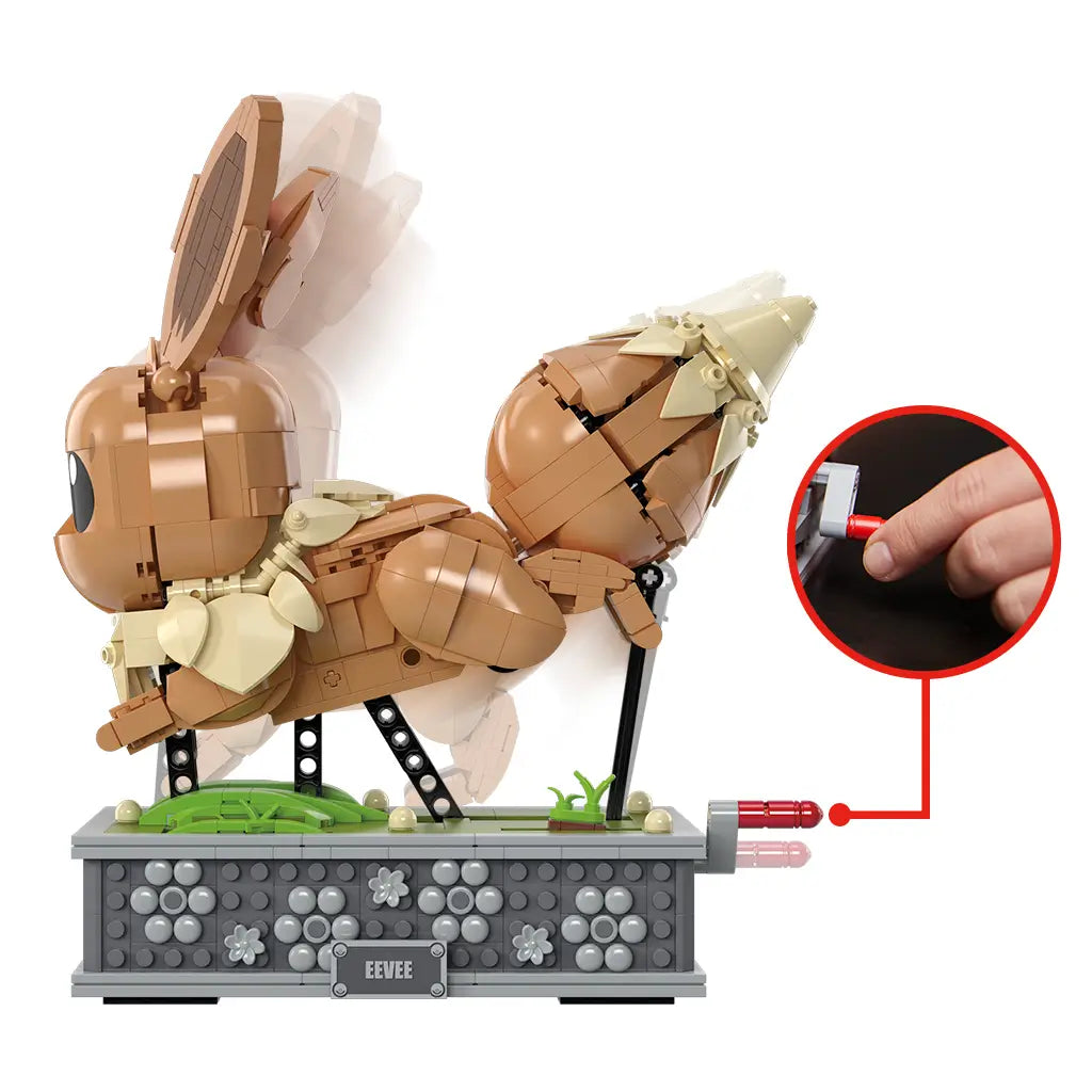 Side view of brown Mega Pokémon Eevee model with hand turning a red crank lever to activate internal gears, animating the figure's walking motion.