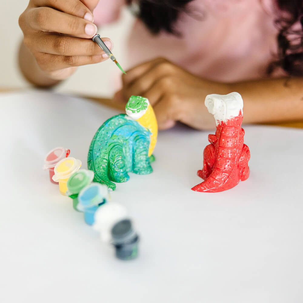 Girl painting dinosaurs from the Melissa and Doug Created by Me! Dinosaur Figurines Craft Kit